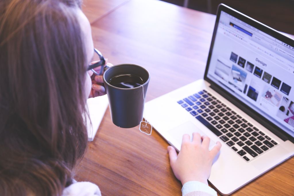 A woman on her laptop with a cup of tea in her hand